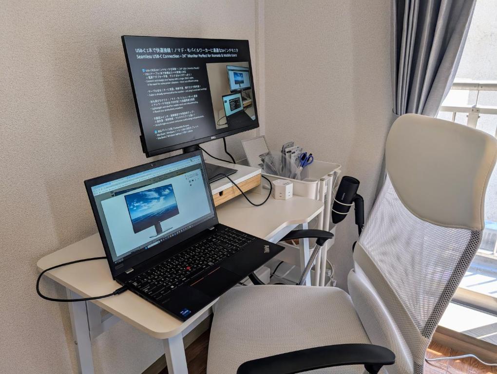 a desk with a laptop and two monitors on it at Nomado Base at YOYOGI in Tokyo