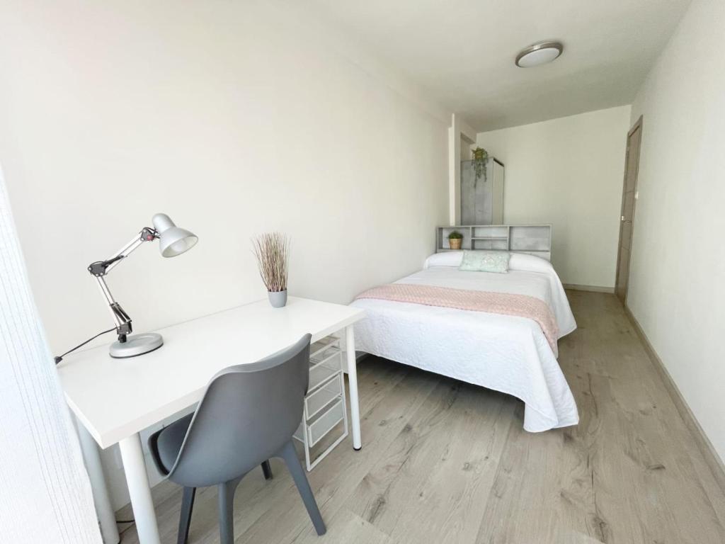 a white bedroom with a desk and a bed at Lacasitadevaleria in Santander