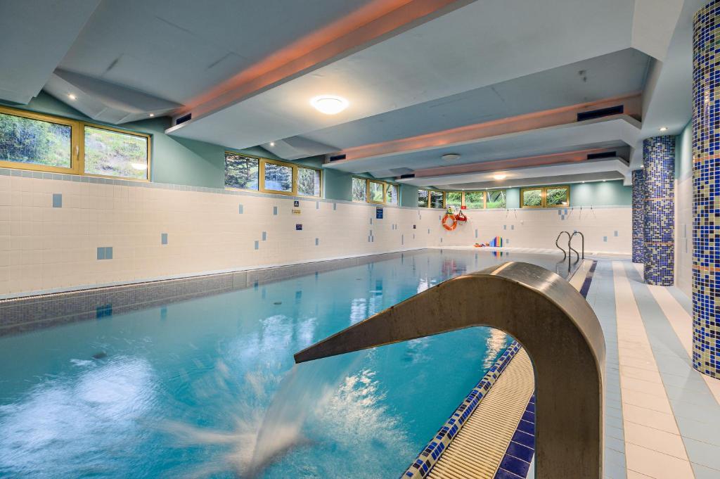a large swimming pool in a gym with a large swimming pool at Apartament W Dolinie Słońca z ogródkiem & SPA in Kościelisko
