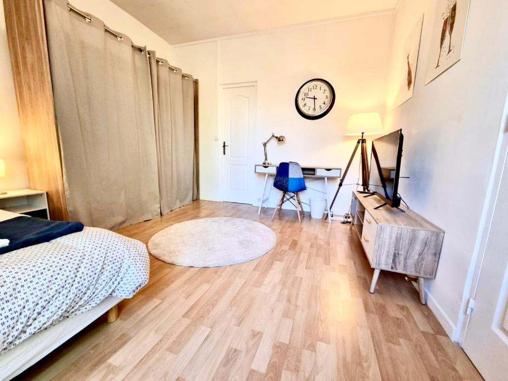 - une chambre avec un lit, un bureau et une horloge dans l'établissement Mont d'arène superbe appartement proche gare, à Reims