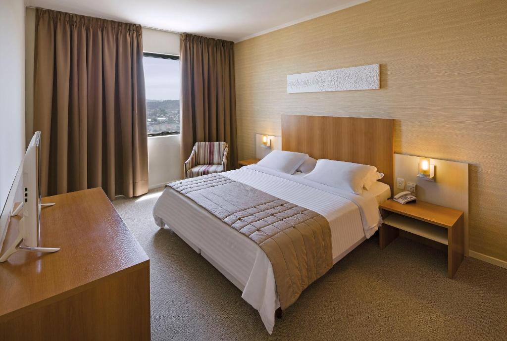um quarto de hotel com uma cama grande e uma televisão em Swan Novo Hamburgo em Novo Hamburgo