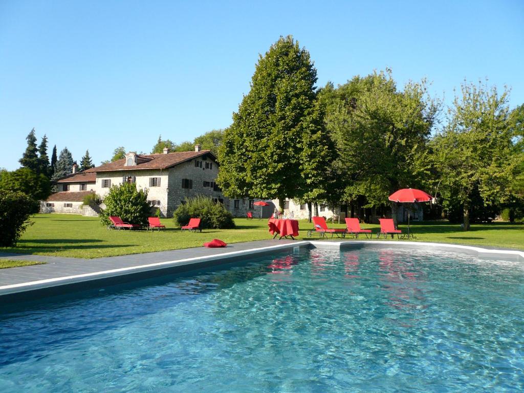 a swimming pool with red chairs and a house at Agriturismo Beria de Carvalho de Puppi in San Giovanni al Natisone