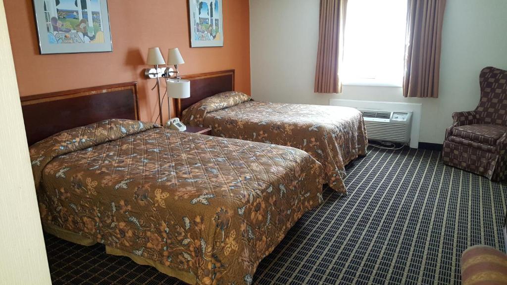 um quarto de hotel com duas camas e uma cadeira em Woonsocket Motor Inn em Woonsocket