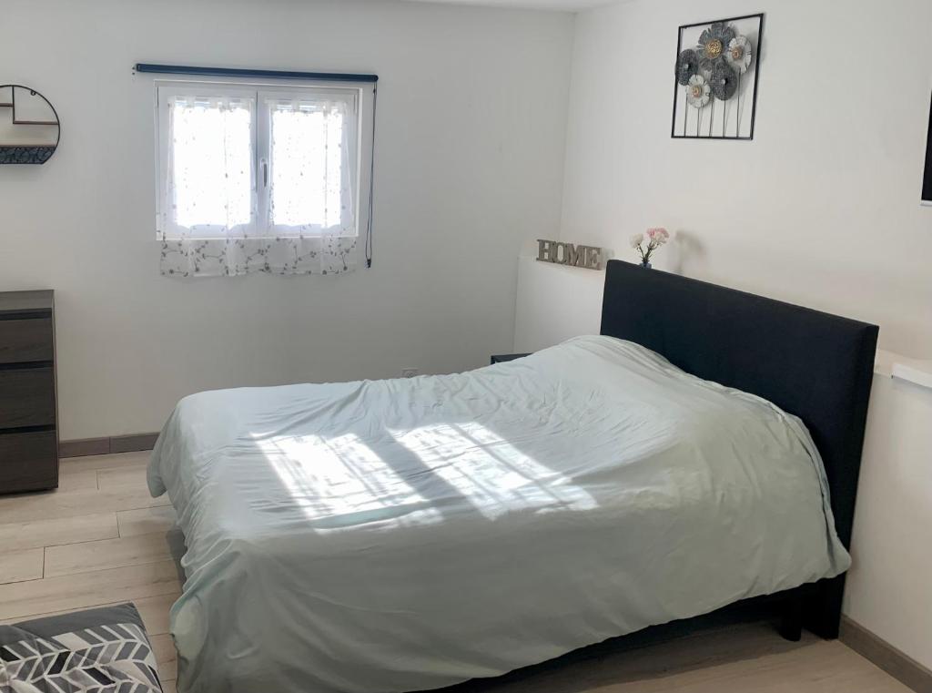 un lit dans une chambre blanche avec une fenêtre dans l'établissement L'Évasion Bayeusaine - Calme et Reposante, à Bayeux