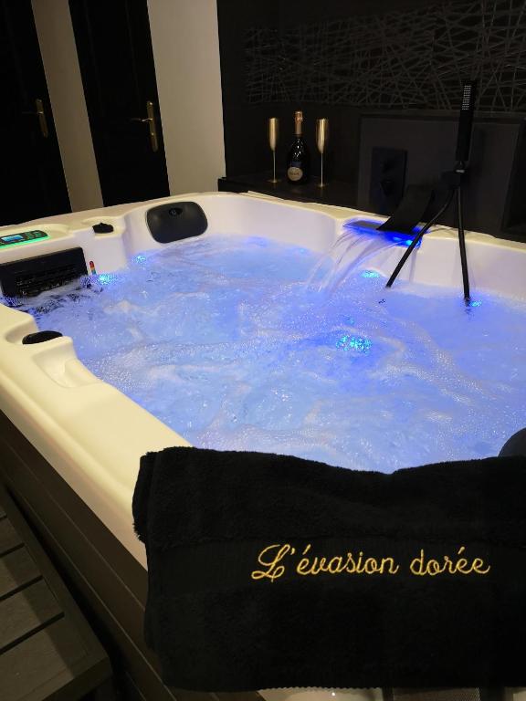 une baignoire remplie d'eau bleue dans une salle de bain dans l'établissement Appartement haut de gamme avec jacuzzi sauna à 5min de la plage à pied, au Havre
