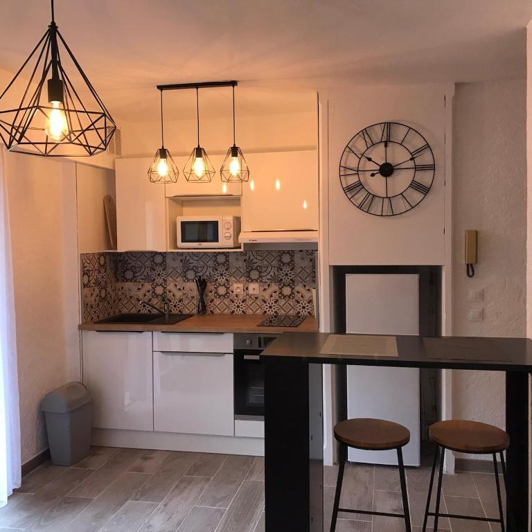 une cuisine avec une table et une horloge au mur dans l'établissement STUDIO CENTRE VILLE avec PARKING PRIVATIF, à Cagnes-sur-Mer