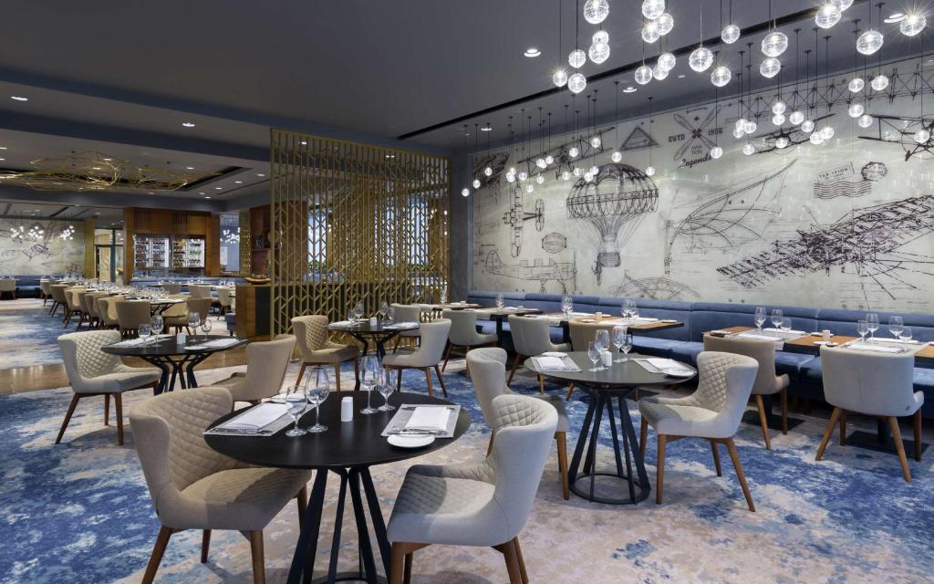 a restaurant with tables and chairs and a mural at DoubleTree By Hilton Moscow - Vnukovo Airport Hotel in Vnukovo