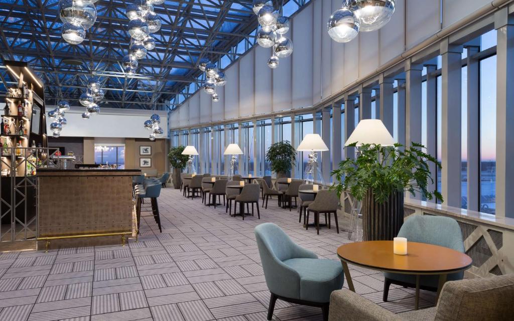 a lobby with tables and chairs in a building at DoubleTree By Hilton Moscow - Vnukovo Airport Hotel in Vnukovo