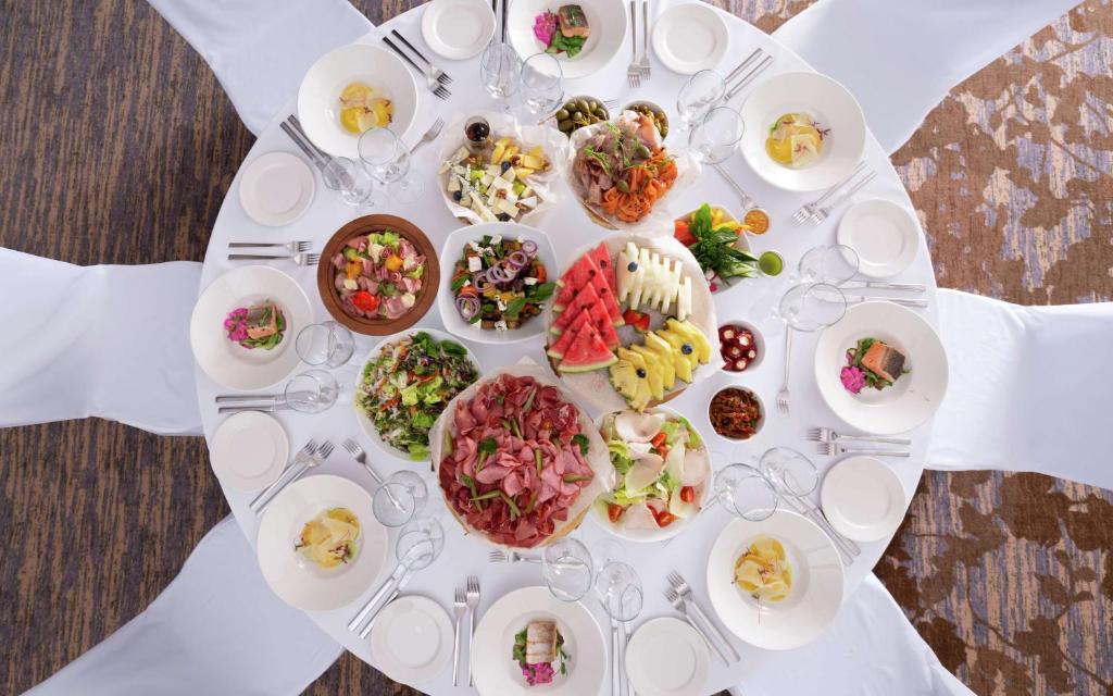 a white table with plates of food on it at DoubleTree By Hilton Moscow - Vnukovo Airport Hotel in Vnukovo