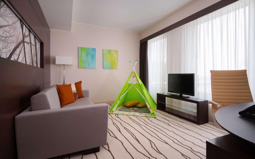 a living room with a couch and a tv at DoubleTree By Hilton Moscow - Vnukovo Airport Hotel in Vnukovo