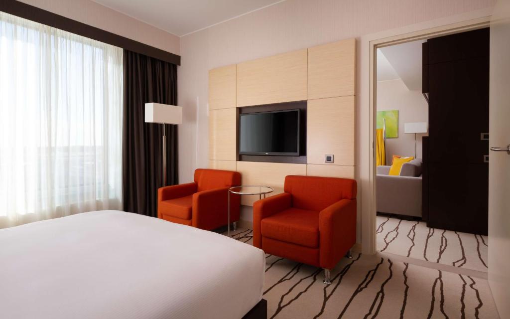 a hotel room with a bed and two chairs and a television at DoubleTree By Hilton Moscow - Vnukovo Airport Hotel in Vnukovo