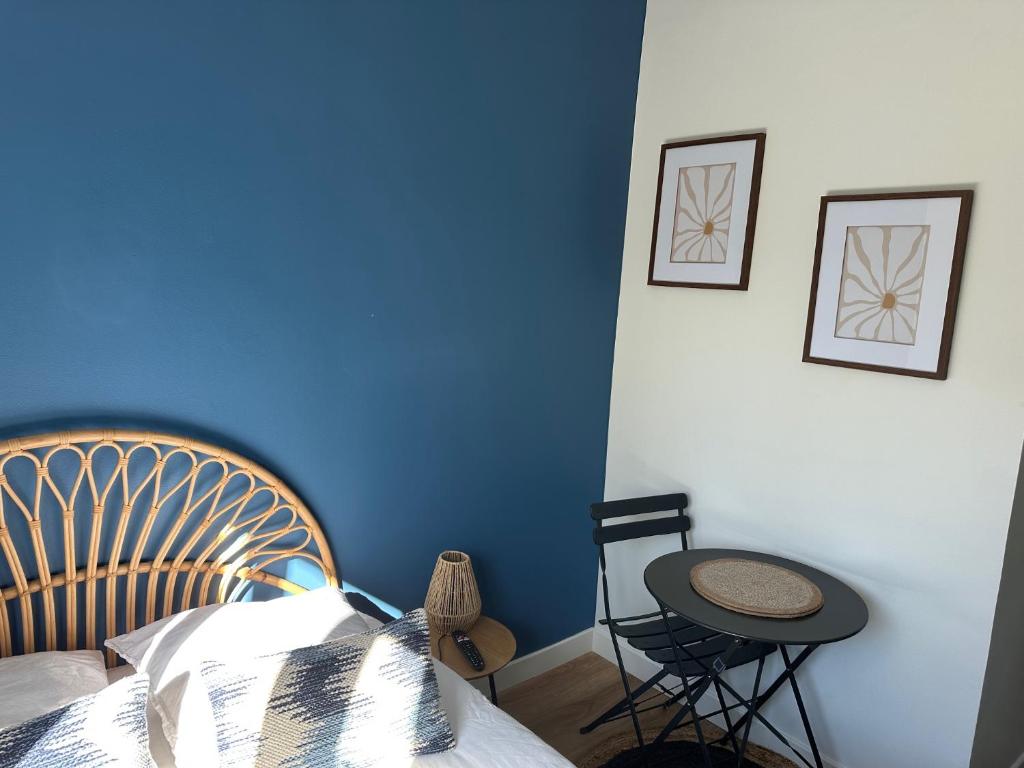 - une chambre dotée d'un mur bleu avec un lit et une table dans l'établissement Les Lilas Gare Centre 2 Pers, au Mans
