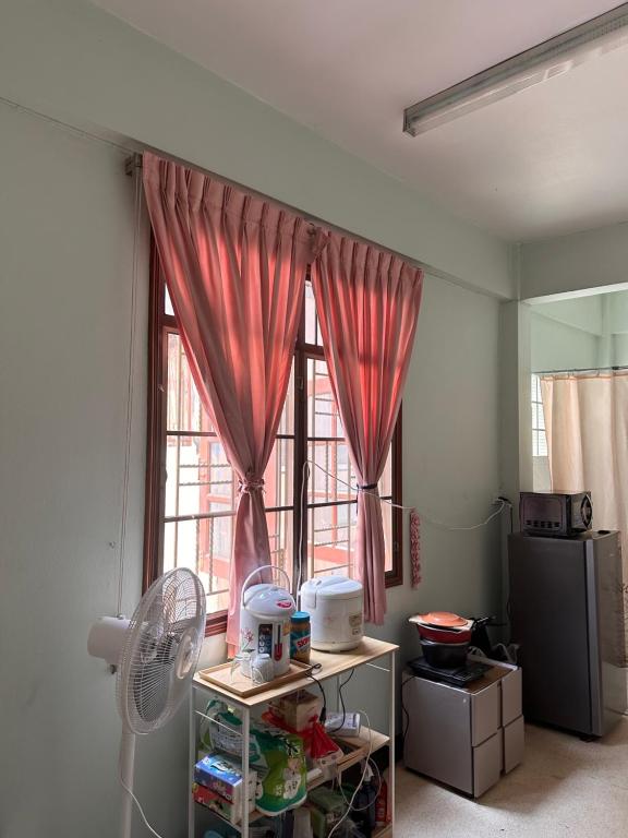 een kamer met een raam met roze gordijnen en een ventilator bij Regalohome Br in Bangkok
