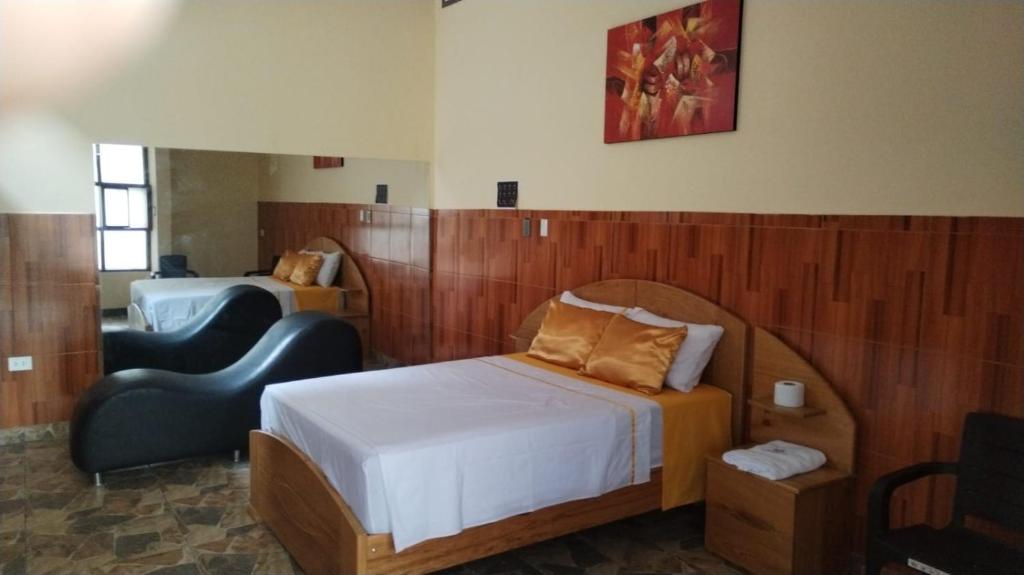 a hotel room with a bed and a chair at La puzanguita suite in Tarapoto