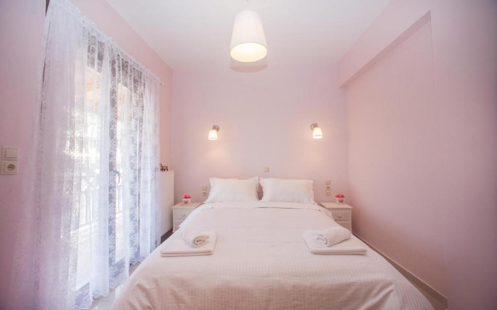 een witte slaapkamer met een groot bed met handdoeken erop bij Olga Dova Apartments in Ioannina