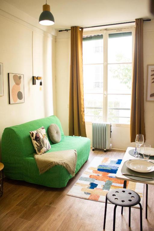 un salon avec un canapé vert et une table dans l'établissement Saint Germain de Près tout équipé - Emplacement exceptionnel au Coeur de Paris, à Paris
