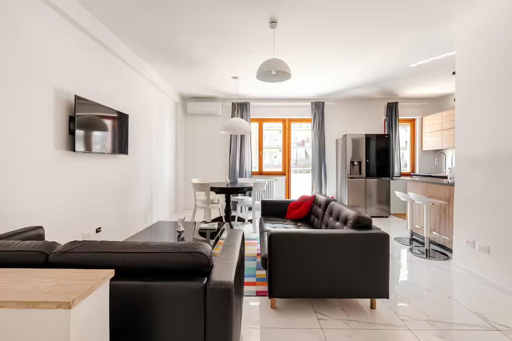 a living room with two black couches and a kitchen at Latina Modern Apartment in Latina