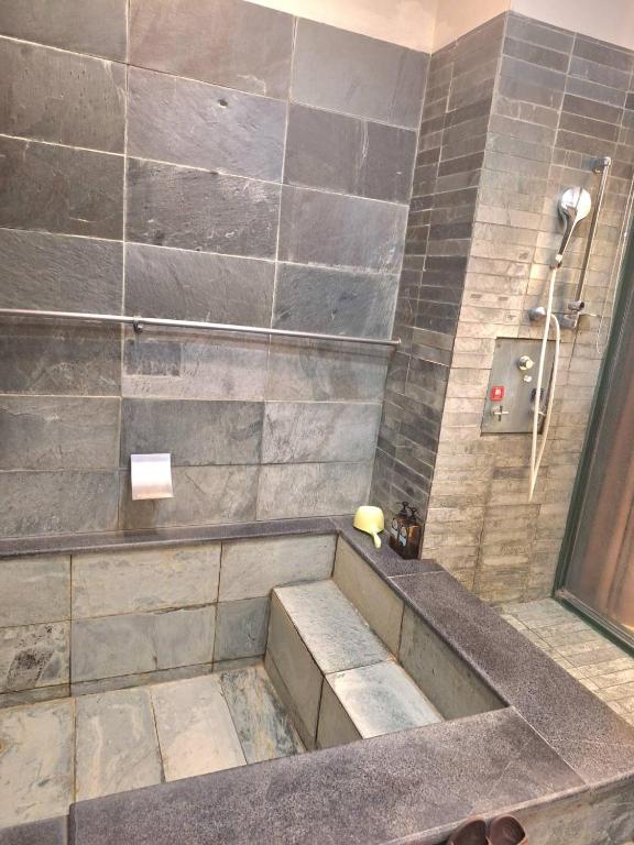 a bathroom with a shower with a stone wall at Valentine湯屋 in Jiaoxi