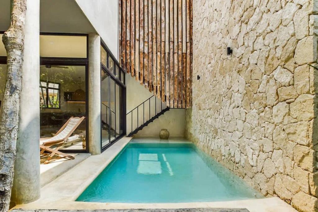 a swimming pool in a house with a stone wall at Boho Jungle Villa -Pvt Pool -Concierge-Hammock 7B in Tulum