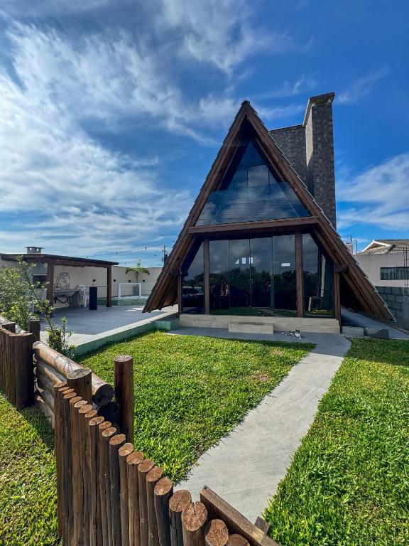 a house with a triangular roof with a wooden fence at Nova cabana com jacuzzi perto do mar in Arroio do Silva