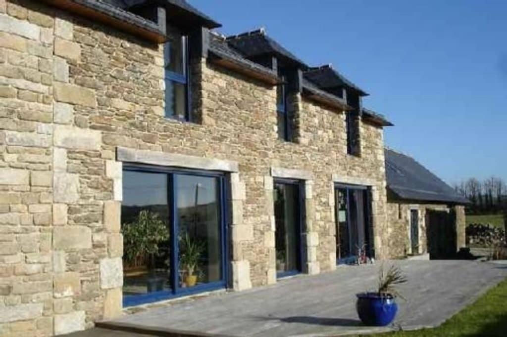 un bâtiment en briques avec une grande porte en verre dans l'établissement longère spacieuse au calme, superbe vue mer, à Loc-Maria-Plouzané