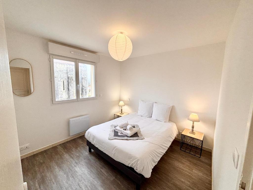 une chambre avec un grand lit blanc avec deux lampes dans l'établissement L'Éclatant, Lumineux, Centre-ville, à Royan
