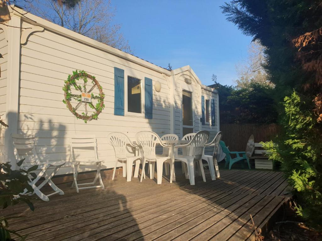 un groupe de chaises blanches et une table sur une terrasse dans l'établissement Mobil home 4 personnes avec clim, à La Roque-dʼAnthéron