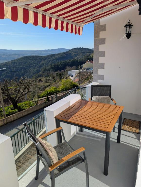 a wooden table and chairs on a balcony with a view at Bela Vista in Paradela
