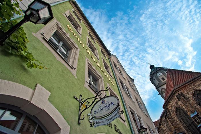 a green building with a sign on the side of it at Schwerter Schankhaus & Hotel in Meißen