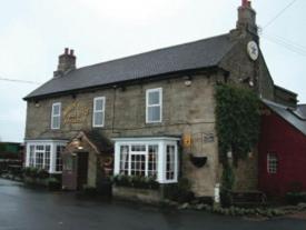 an old brick building with a clock on it at Robin Hood Inn in Wall Houses