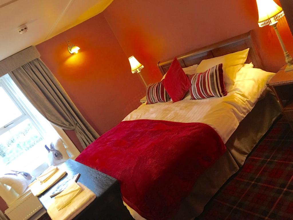 a bedroom with a large bed with red and yellow pillows at Robin Hood Inn in Wall Houses
