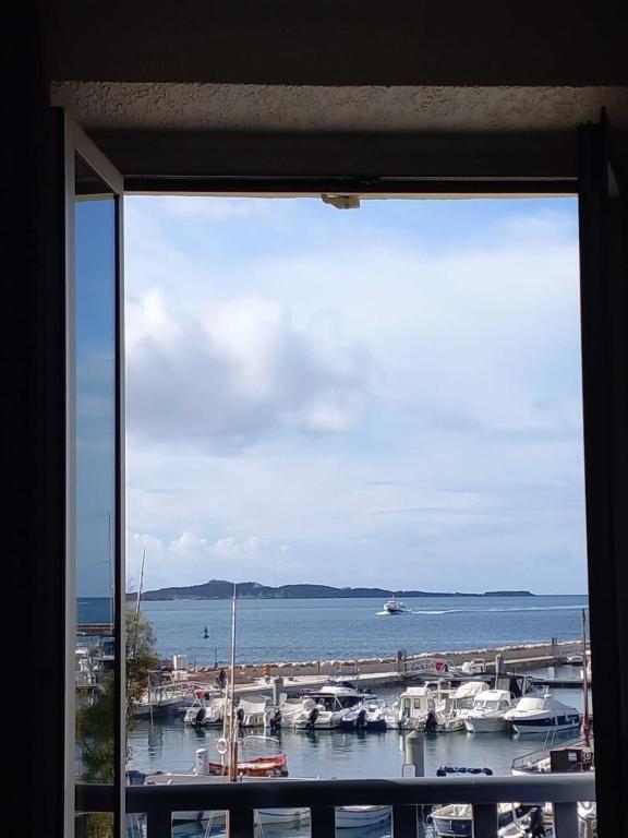 une fenêtre donnant sur un port de plaisance avec des bateaux dans l'eau dans l'établissement Pied à terre, séjour idyllique face à la mer classé 2 étoiles, à Sanary-sur-Mer