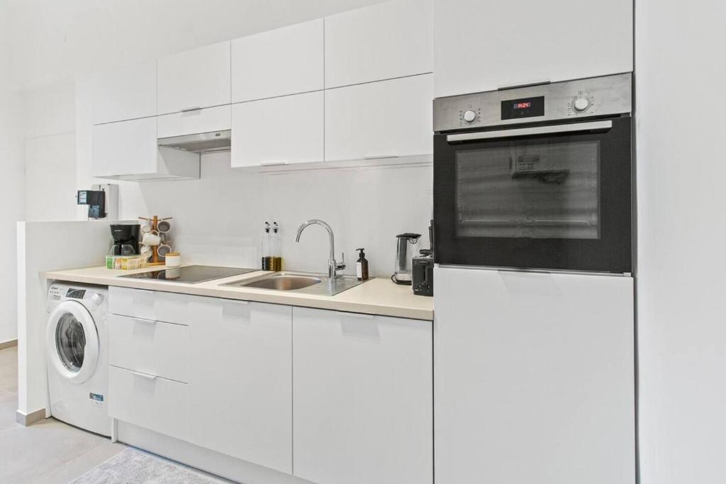 a white kitchen with a sink and a dishwasher at Fast Wifi I 4 min to U3 Zipperer Straße in Vienna