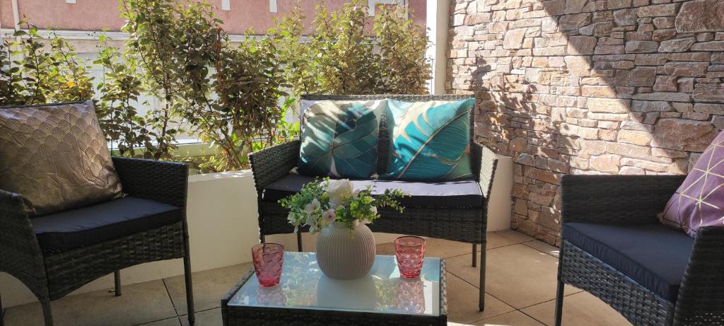 une terrasse avec 2 chaises et une table avec un vase dans l'établissement Appartement neuf à 100 m de la plage - New 100m from beach, à Fréjus