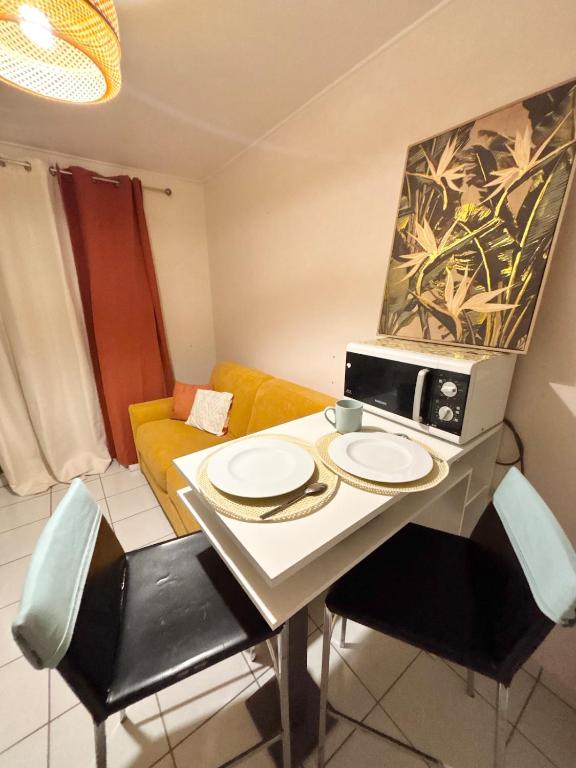 a small kitchen with a table with plates and a microwave at Le Tiny Studio in Saint-Denis