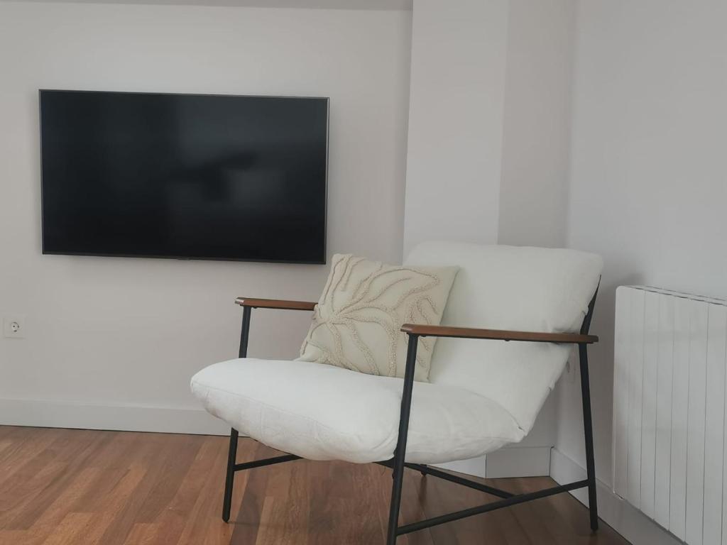 une chaise blanche assise devant une télévision dans l'établissement Apartamento AIIA, à Ribadeo