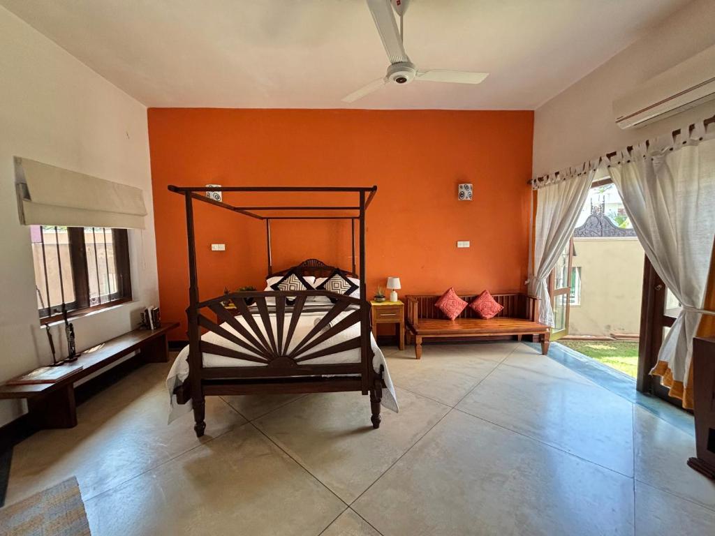 a room with an orange wall with a bed in it at Villa Plum Colombo in Battaramulla