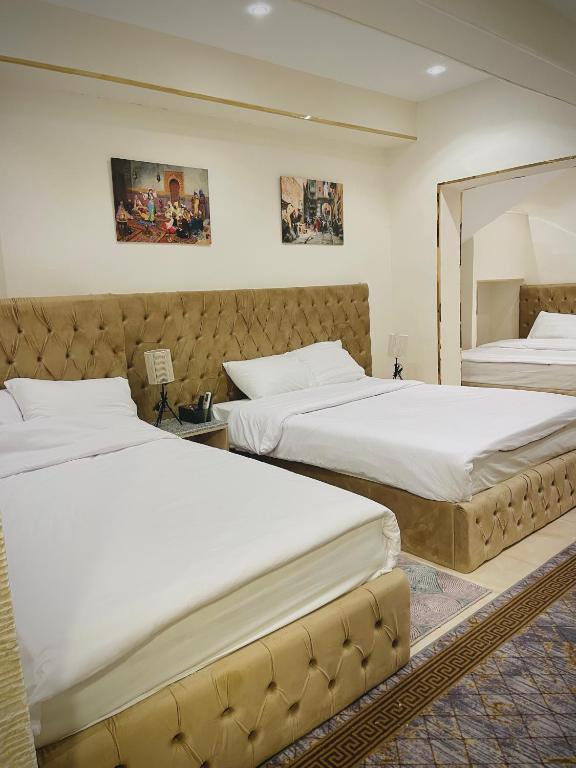 two beds in a hotel room with white sheets at Sunrise Family Big Room in Cairo