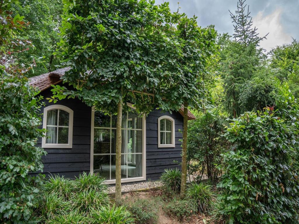 una casa negra con ventanas blancas y árboles en Forest Farmhouse w Private Garden, en Ermelo