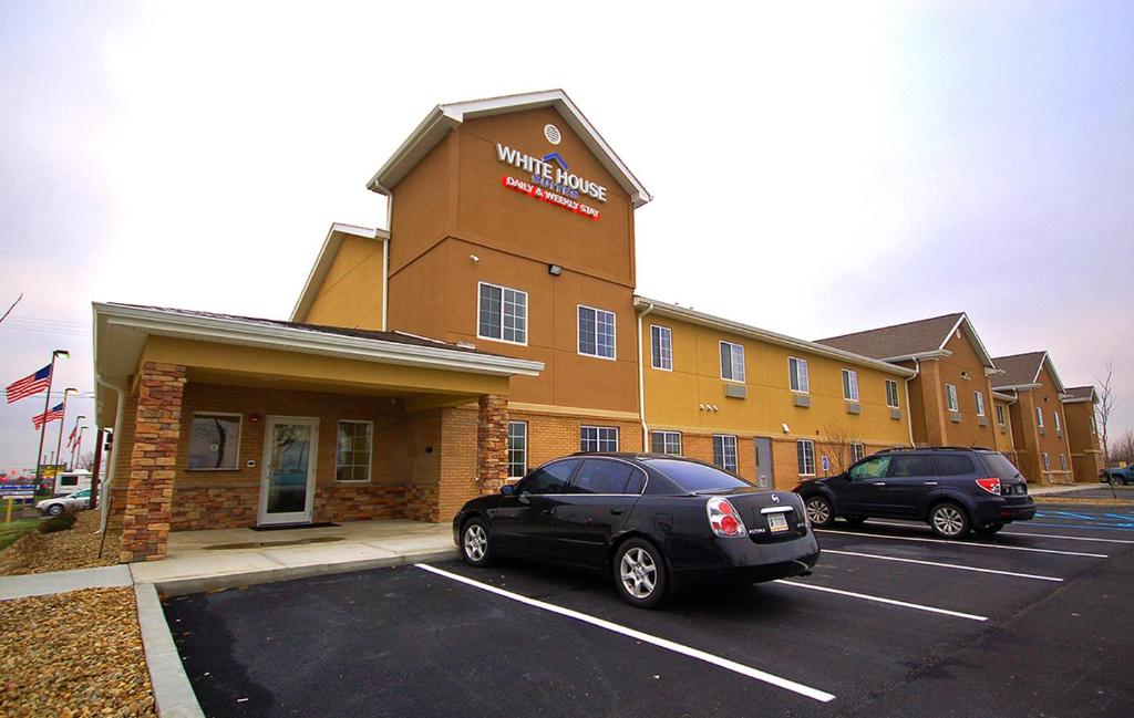 dos coches estacionados en un estacionamiento frente a un hotel en White House Suites en Plainfield