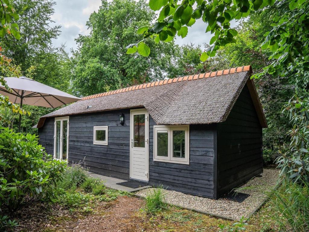 a small black shed with a white door at Pets Welcome, Veluwe Farmhouses for All in Ermelo