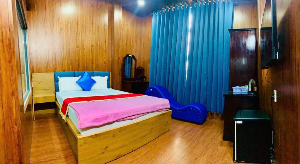 a bedroom with a bed and blue curtains in it at royal hotel bà điểm hồ chi minh in Ho Chi Minh City
