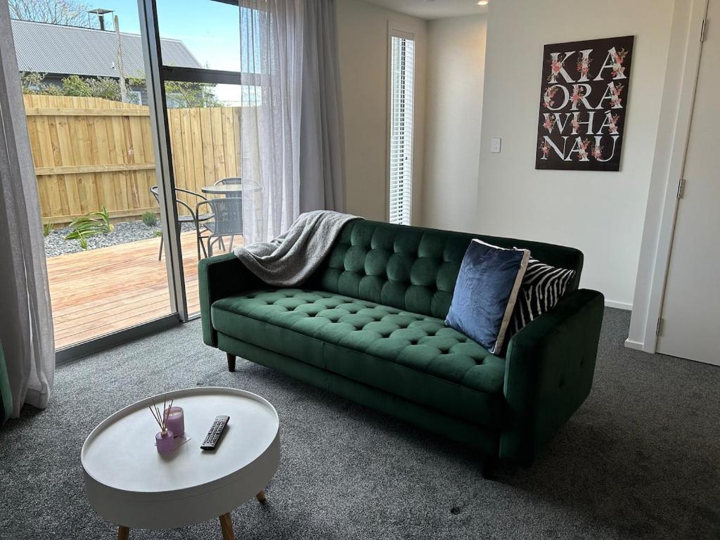 Una sala de estar con un sofá verde y una mesa. en Apartment 5 on Armagh!, en Christchurch