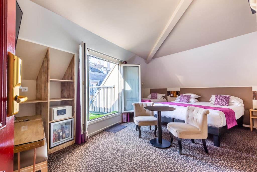 a bedroom with a bed and a table and chairs at hotel Louvre Sainte Anne in Paris
