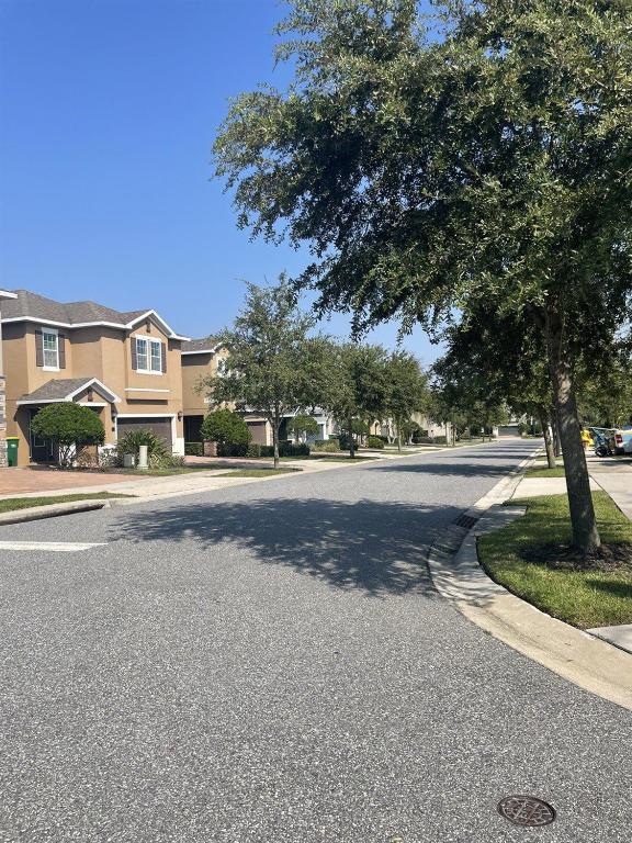 an empty street with a tree in a residential neighborhood at 491-8-LD-Private Pool with Game and Movie in Orlando