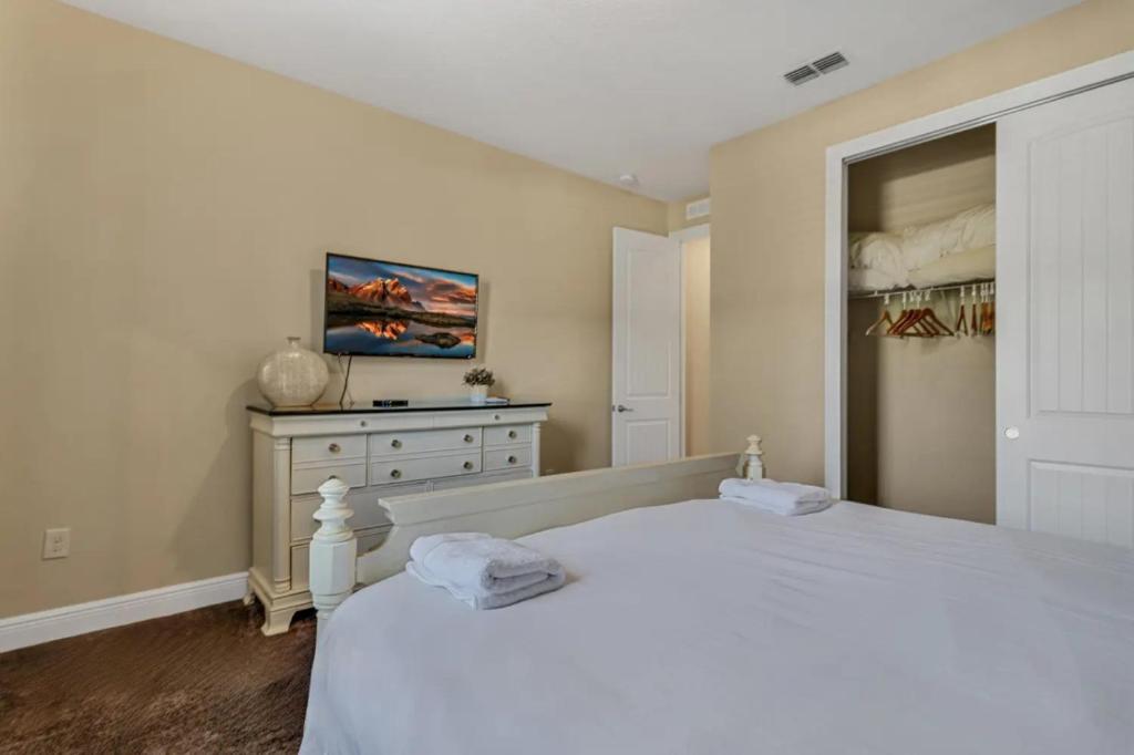a bedroom with a white bed and a dresser at 491-8-LD-Private Pool with Game and Movie in Orlando