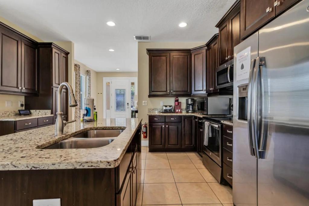 a kitchen with wooden cabinets and stainless steel appliances at 491-8-LD-Private Pool with Game and Movie in Orlando