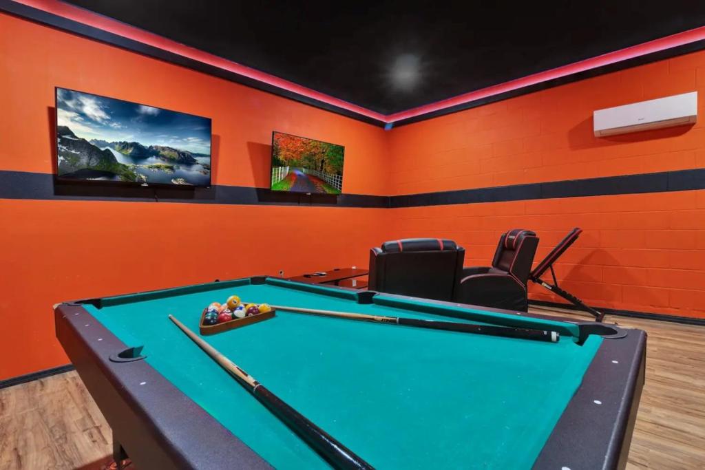 a pool table in a room with an orange wall at 491-8-LD-Private Pool with Game and Movie in Orlando