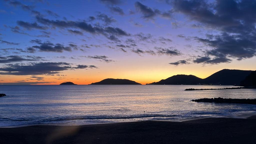 a sunset over the ocean with mountains in the background at SalutieBaci in Lerici