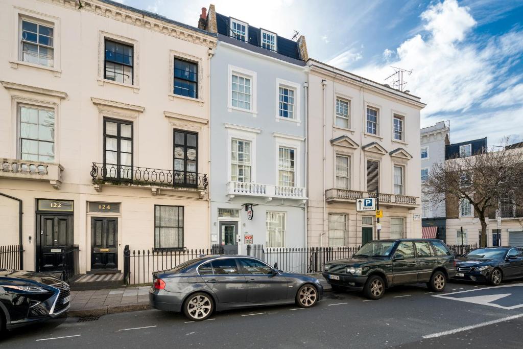 two cars parked in front of a large white building at OYO Bakers Hotel London Victoria in London